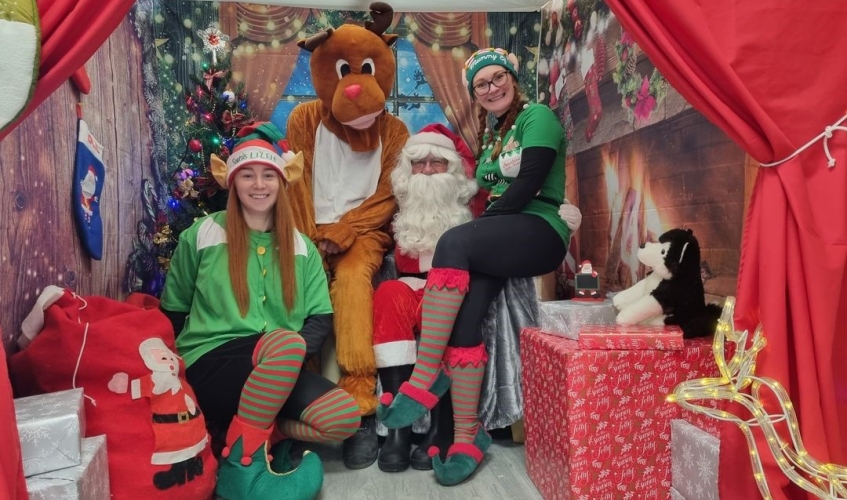 people dressed as elves, reindeer and santa inside a santas grotto