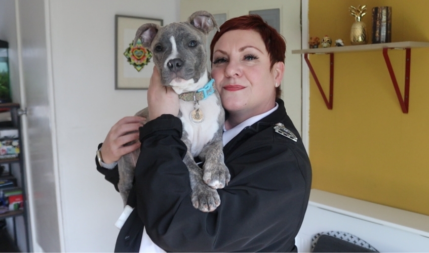 Scottish SPCA inspector looking at the camera and holding up and grey and white dog