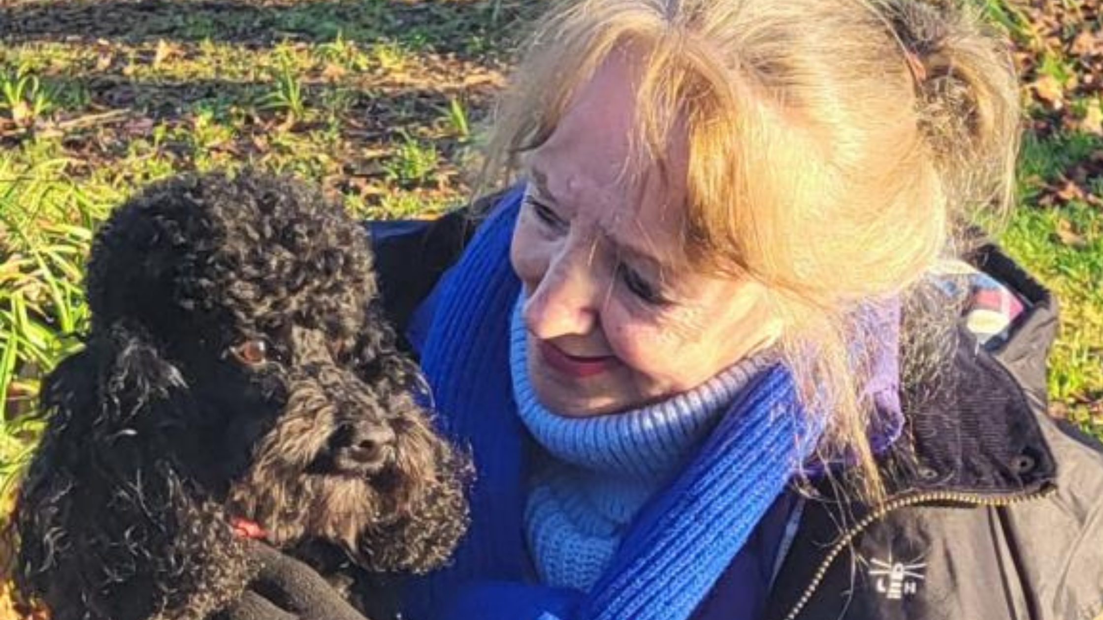 Dog and woman cuddling on a park walk